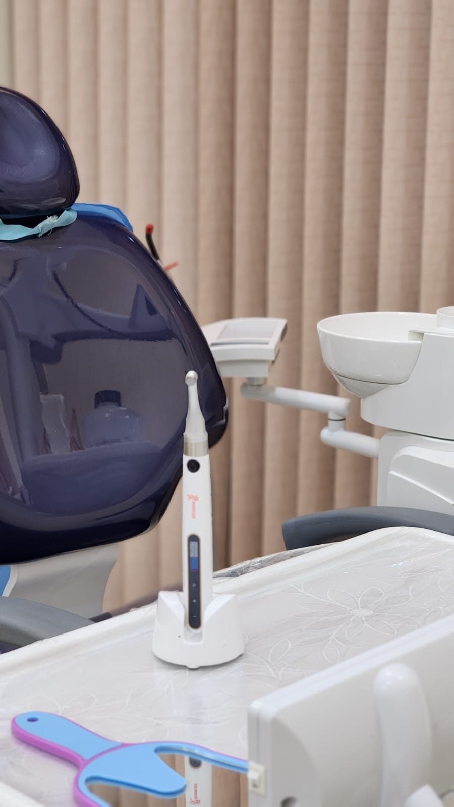 Close-up of a dental instrument resting on the tray beside the chair